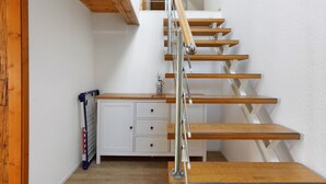Una escalera de madera con barandas de metal, armarios blancos y un radiador.