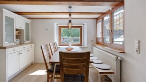 Un comedor con una mesa de madera, sillas, un bol y una ventana con vistas.