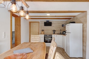 Eine Küche mit Holzbalken, einem weißen Kühlschrank, einem Herd und einem Holzespeisetisch.
