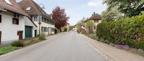 Een rustige woonstraat met huizen, een heldere lucht en een keurig onderhouden voetpad.