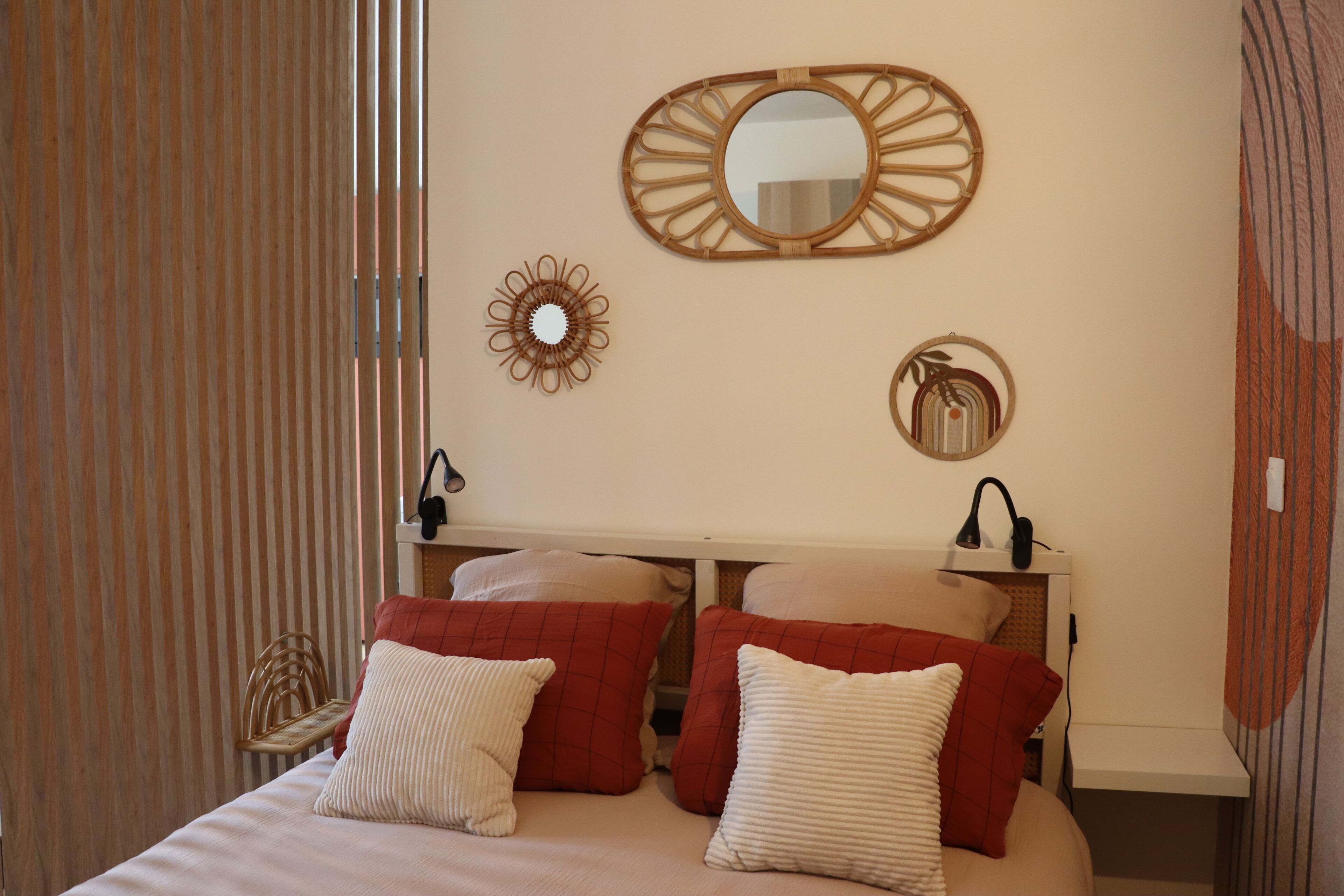 A bedroom with a bed, pillows, a bedside table, a mirror, and wall decor.