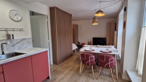 A compact kitchen with a sink, a clock, and a dining area with a table and chairs. - Cosy, quiet studio in the historic center of Senlis (Senlis)