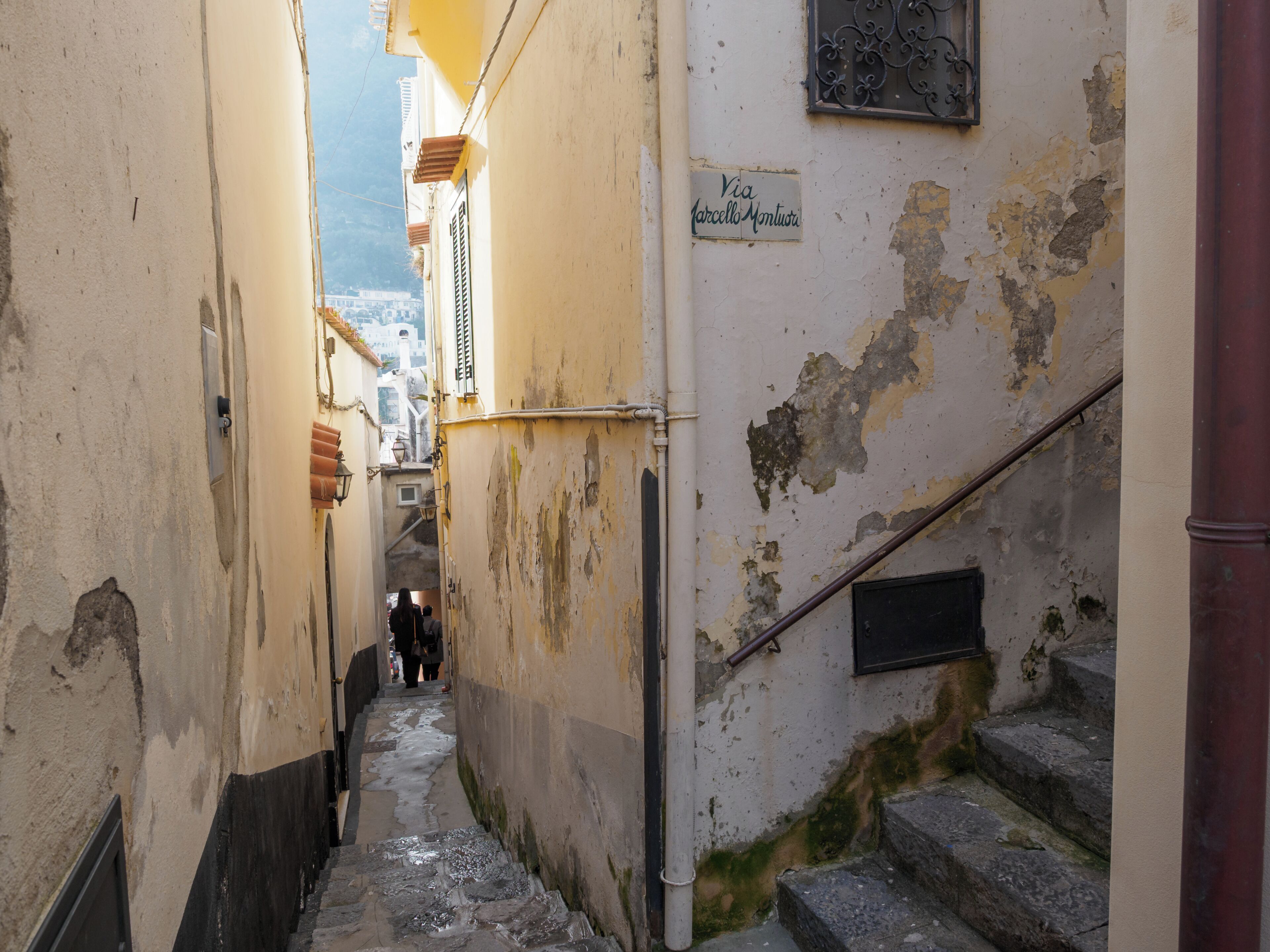 Une ruelle étroite avec un escalier menant à l’entrée d’un immeuble.
