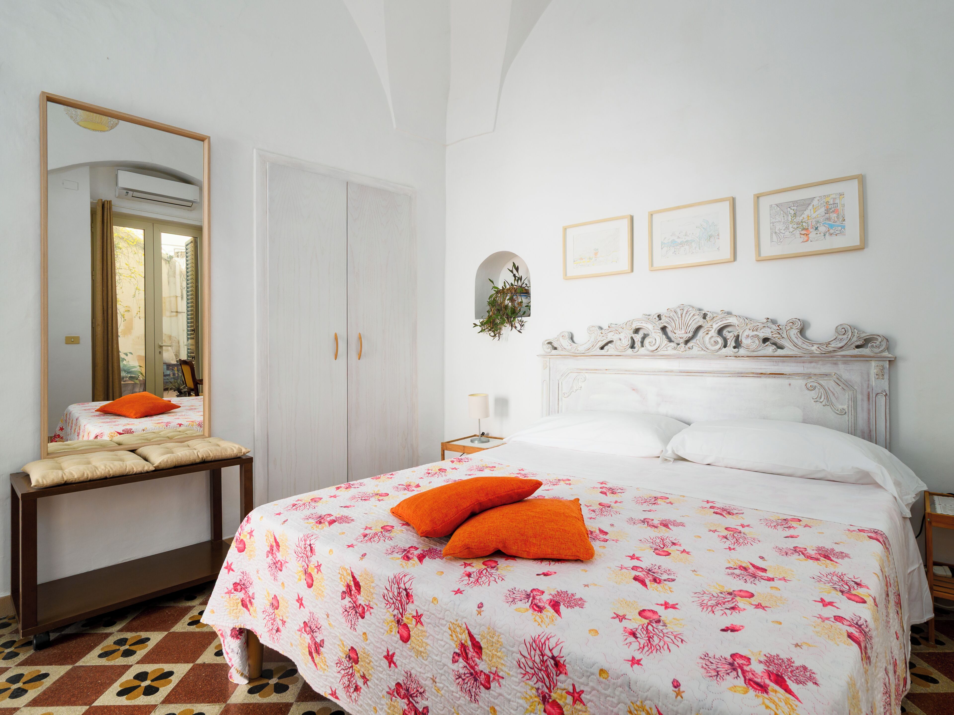 A bedroom with a bed, a bedside table, a mirror, and a wardrobe.