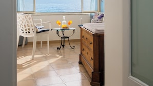 A room with a view of the sea, a table with a bottle and glasses, a chair, and a dresser. - De Vivo Realty - La casa del Cavaliere (Positano)