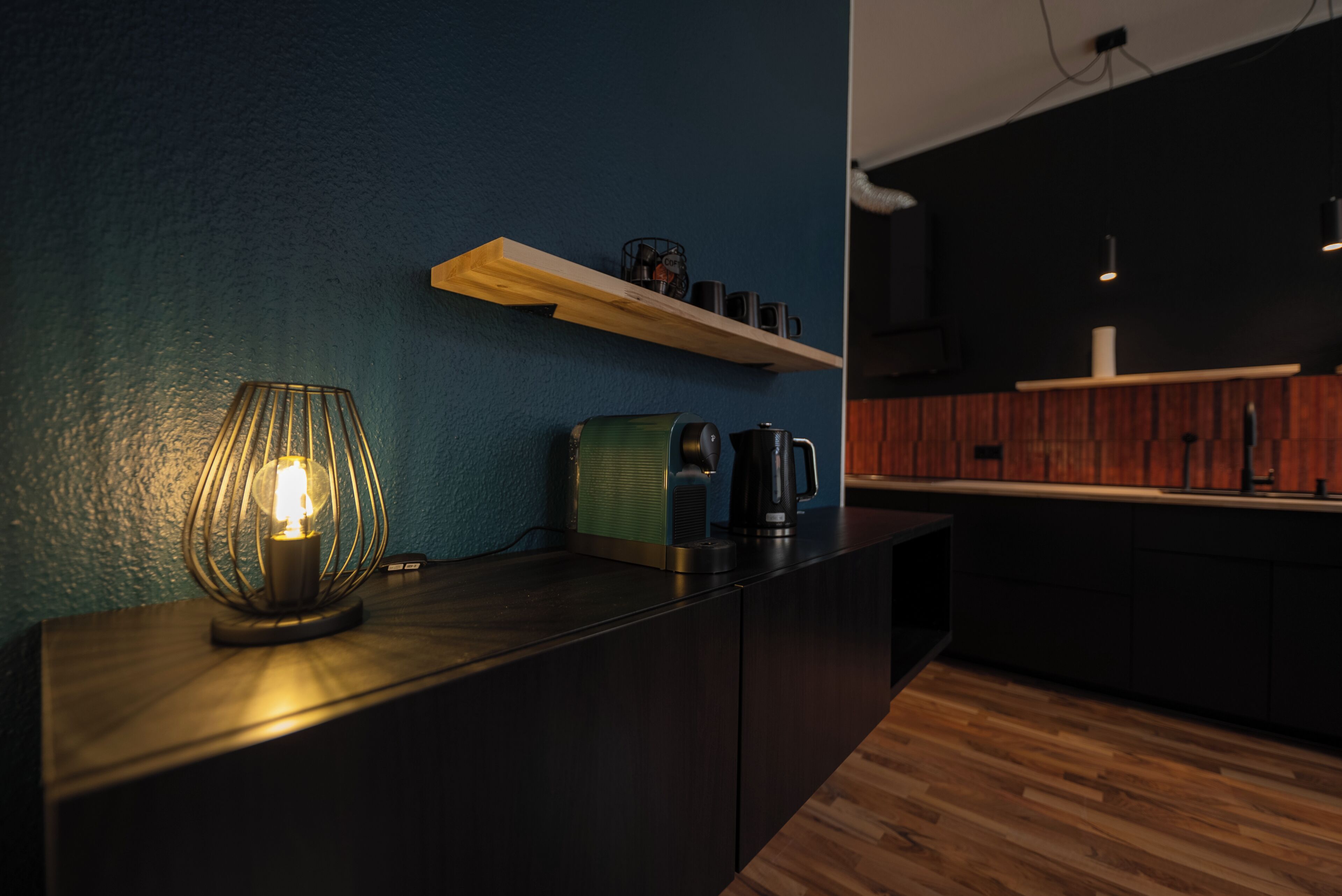 Une cuisine moderne dotée d’un plan de travail en bois, d’une machine à café et d’une étagère contenant des ustensiles de cuisine.