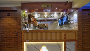 Un área de recepción con mostrador de madera, una barra de mármol y un reloj de pared.