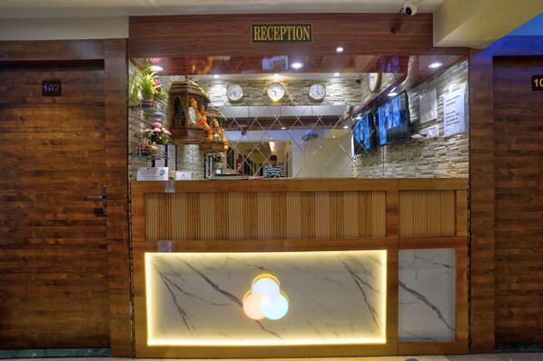 A reception area with a wooden reception desk, a marble counter, and a wall clock.