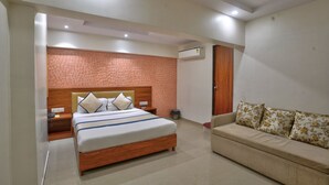 Habitación de hotel con cama, sofá, mesita de noche, aire acondicionado y una pared con diseño decorativo.