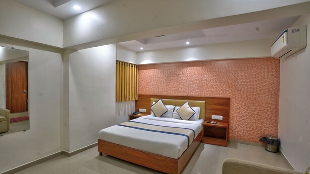 Habitación de hotel con cama, mesitas de noche, un espejo, aire acondicionado de pared y pared con diseño.