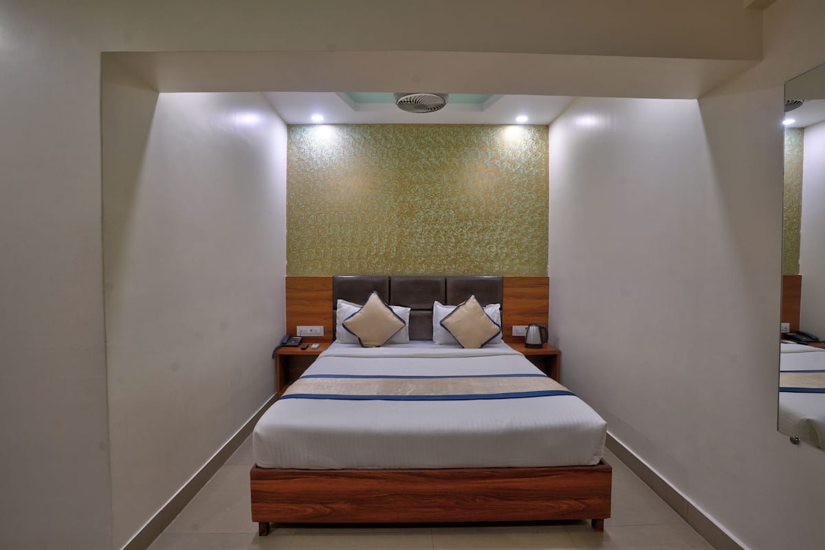 A hotel room with a bed, nightstands, a mirror, and a textured wall.