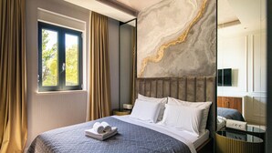 A hotel room with a bed, a bedside table, a TV, and a window with curtains. - DUBROVNIK VISTA RESIDENCE by DuHomes  (Dubrovnik)