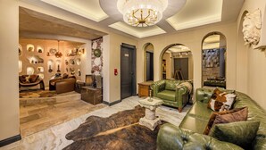 A spacious lobby with a chandelier, leather sofas, a bullhide rug, and a display of decorative items. - White Mansion Cappadocia (Nevşehir)