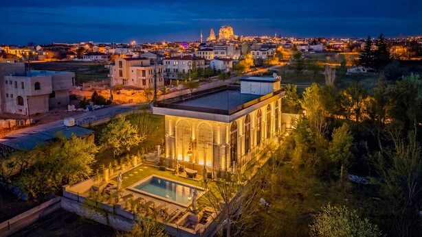 A modern building with a pool, surrounded by greenery, and a cityscape in the background. - White Mansion Cappadocia (Nevşehir)