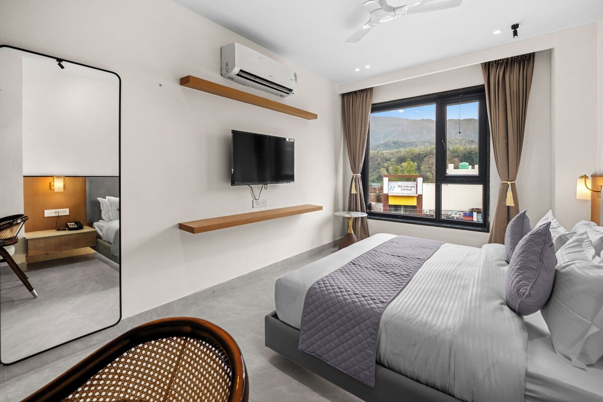 Ein modernes Hotelzimmer mit Bett, Fernseher, Fenster mit Blick und Deckenventilator.