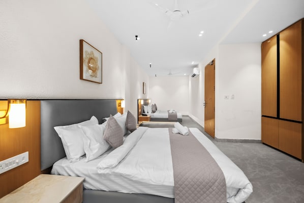 Ein modernes Hotelzimmer mit einem großen Bett, Nachttischen, einem Kleiderschrank und einem Spiegel.