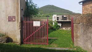 Une entrée fermée par un portail, agrémentée d’un panneau indicateur, d’un mur en pierre et d’une pelouse parsemée de fleurs jaunes.