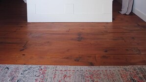 Une chambre à coucher avec un plafond en bois, un lit avec une tête de lit, deux tables de chevet et une fenêtre avec des rideaux.