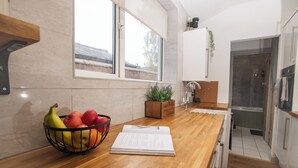Eine Küche mit Holztischplatte, Obstschale, Blumentopf und einem Fenster.