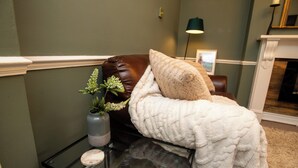 Ein Zimmer mit einem Bett, einem Glastisch mit Vase und Kerze sowie einem Kamin.