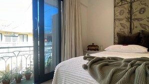 Un dormitorio con cama, un ventanal y vistas al exterior.