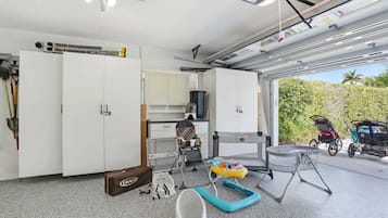 A garage with a carport, a baby stroller, a baby walker, a baby seat, and a storage cabinet.