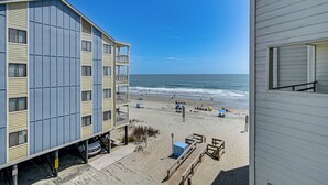 Ett hotell vid stranden med en balkong, en sandstrand och havet som bakgrund.