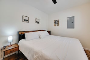 A neatly made bed with white linens, a bedside table with a lamp, and a power outlet. - Lake Cumberland Views! Boating & Fishing Basecamp (Somerset)