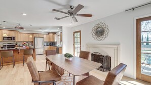 Una cocina moderna con armarios de madera, una zona de comedor con mesa y sillas, un ventilador de techo y una chimenea.