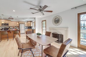 Eine moderne Küche mit Holzausstattung, ein Essbereich mit Tisch und Stühlen, ein Deckenventilator und ein Kamin.