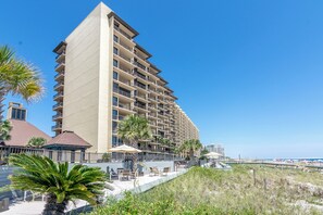 Un hotel de varios pisos con balcones, vista al mar y zonas de estar al aire libre.