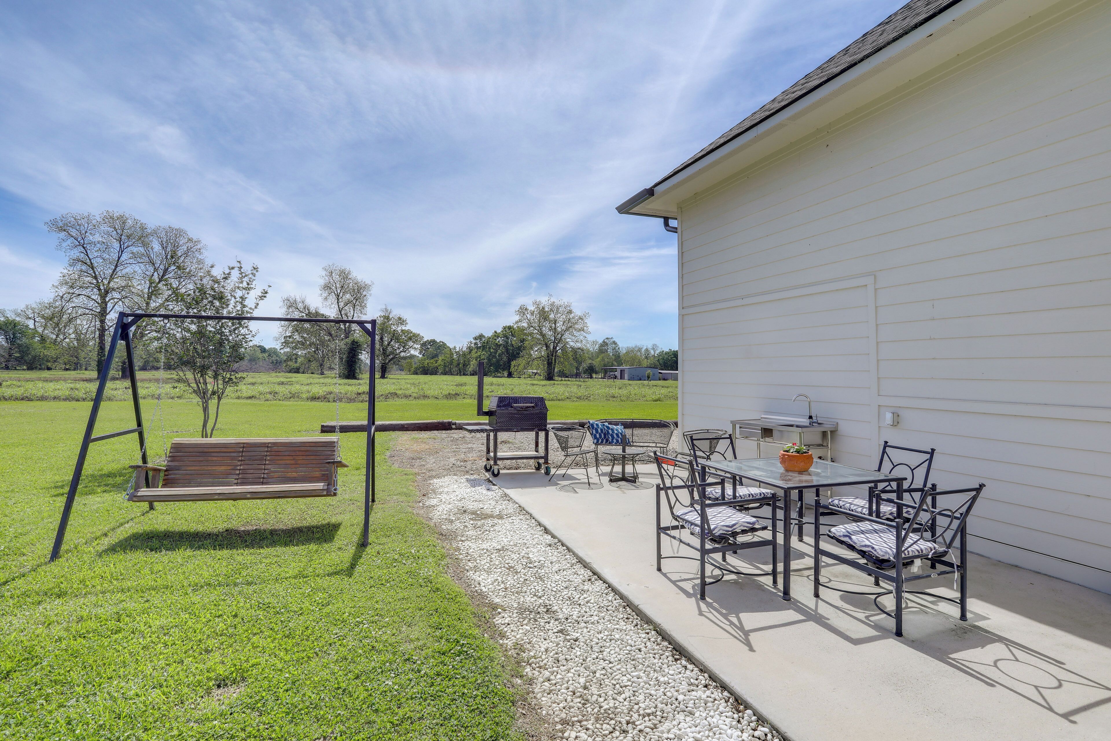 A patio with a swing set, outdoor seating, and a grill area.
