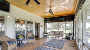 A covered porch with wicker furniture, patterned rugs, and a ceiling fan. - Serene Lake-view Oasis & River Retreat (Ventress)