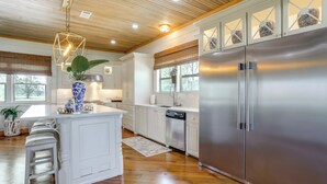 A kitchen with a large island, stainless steel appliances, and wooden flooring. - Serene Lake-view Oasis & River Retreat (Ventress)