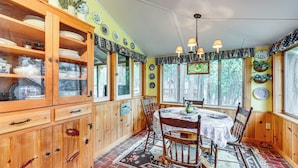 A wooden dining room with a table and chairs, a cabinet with dishes, and a patterned rug. - Gateway to Sequoia Natl! Rustic Cabin w/ Patio (Camp Nelson)