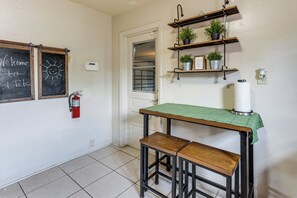 Eine Küche mit einer Kreidetafel, Holzstühlen und Regalen mit Pflanzen.