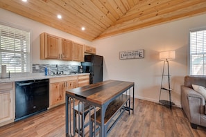 A modern kitchen with wooden cabinets, a black dishwasher, a wooden dining table with benches, a black refrigerator, and a 'Welcome to our Lakehouse' sign. - Lakeside Views! Somerset Escape 1 Mi to Boat Ramp (Somerset)