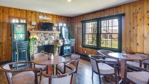 Um quarto com paredes de madeira, uma lareira de pedra, uma televisão e um letreiro da Budweiser.