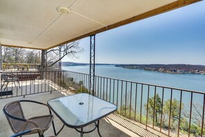 Ein Balkon mit Tisch und Stühlen mit Blick auf ein Gewässer und entferntes Land.