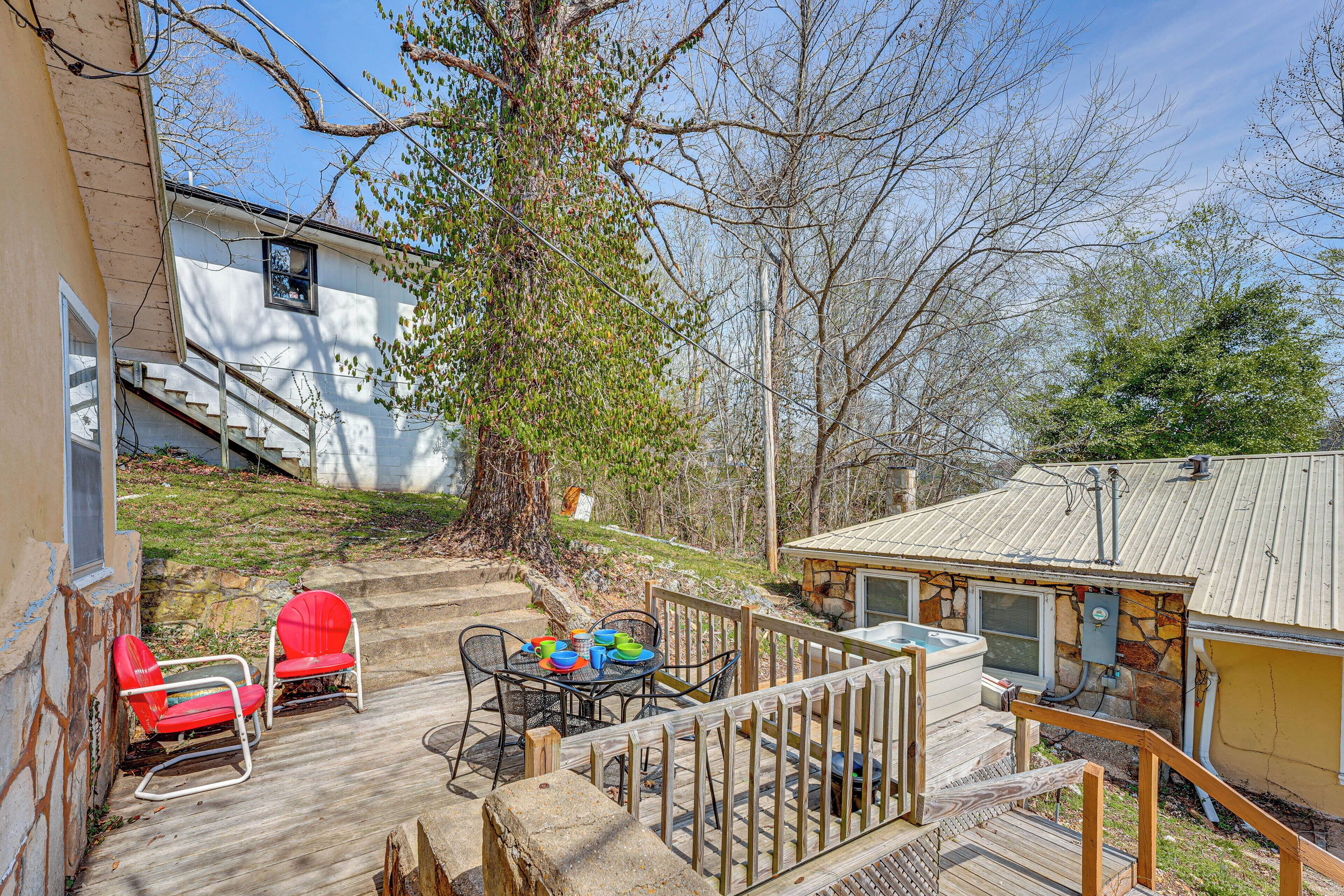 A deck with outdoor furniture, a hot tub, and a stone house with a metal roof.