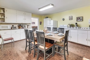 Een keuken met witte kastjes, een houten eettafel en stoelen.