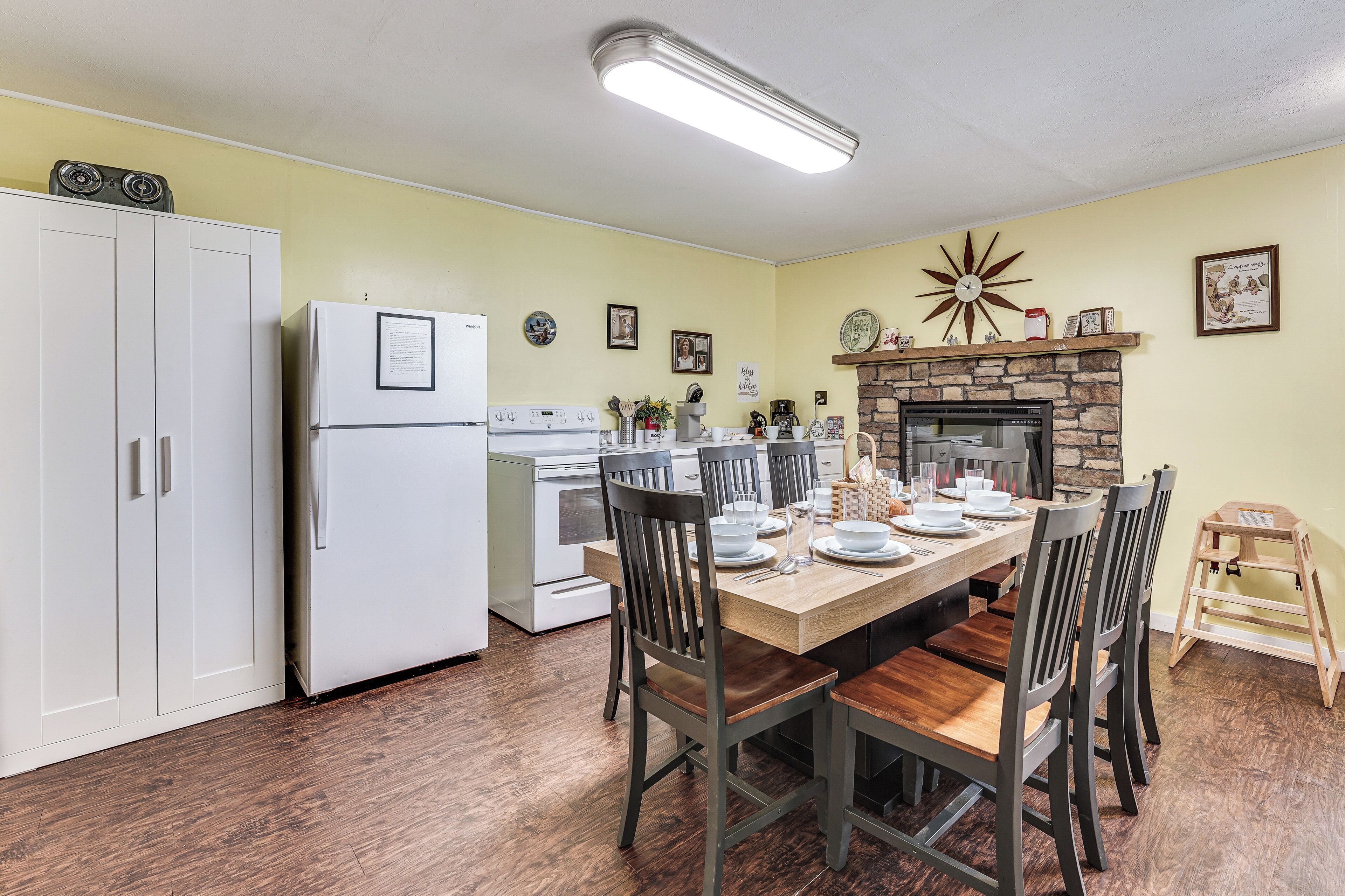 Una cocina con mesa, sillas, refrigerador, horno y chimenea.