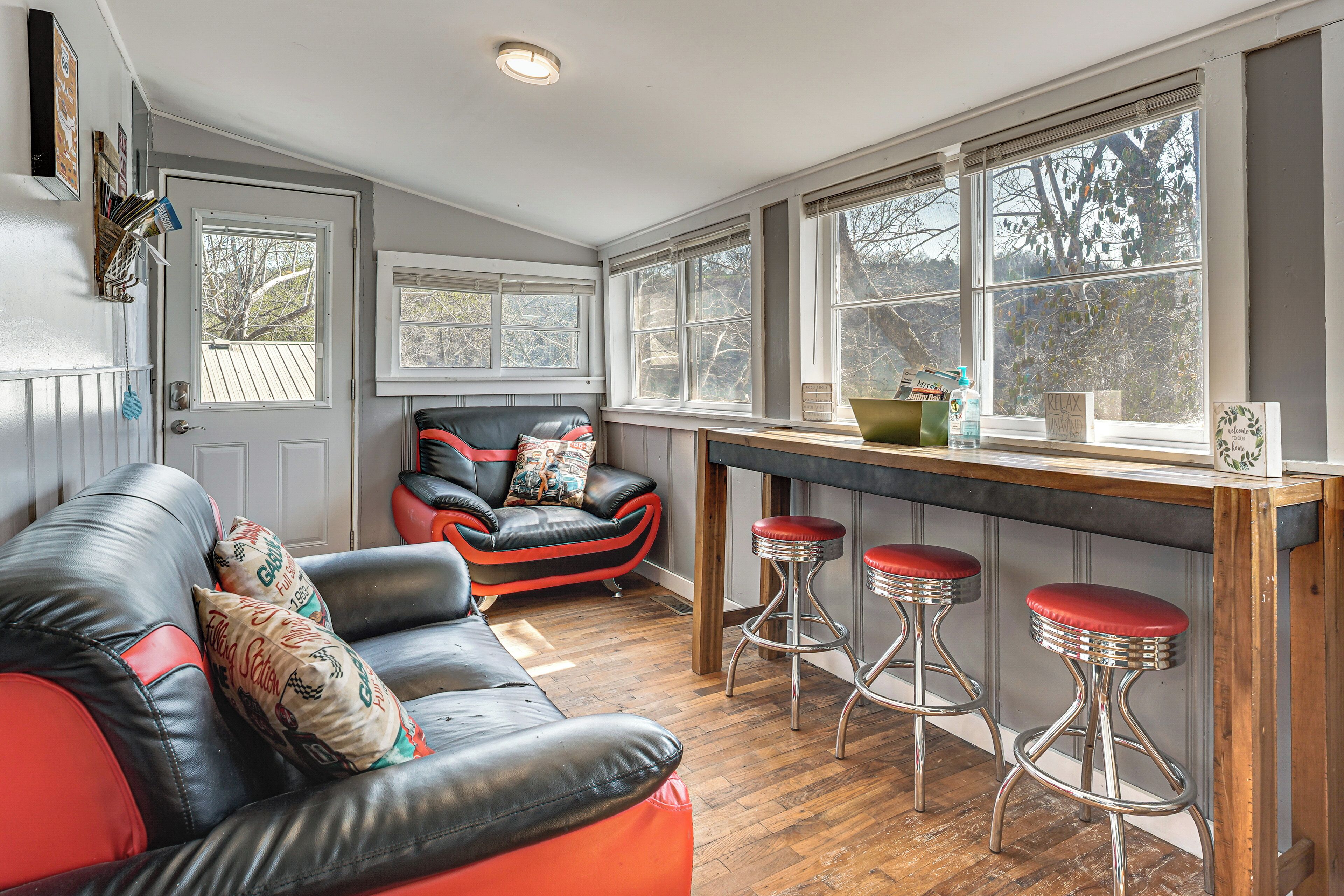 A room with a leather sofa, a bar area with stools, and large windows.