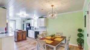 A kitchen with wooden cabinets, a dining table with chairs, and a chandelier. - Explore Tupelo & Natchez Trace! Southern Getaway (Tupelo)