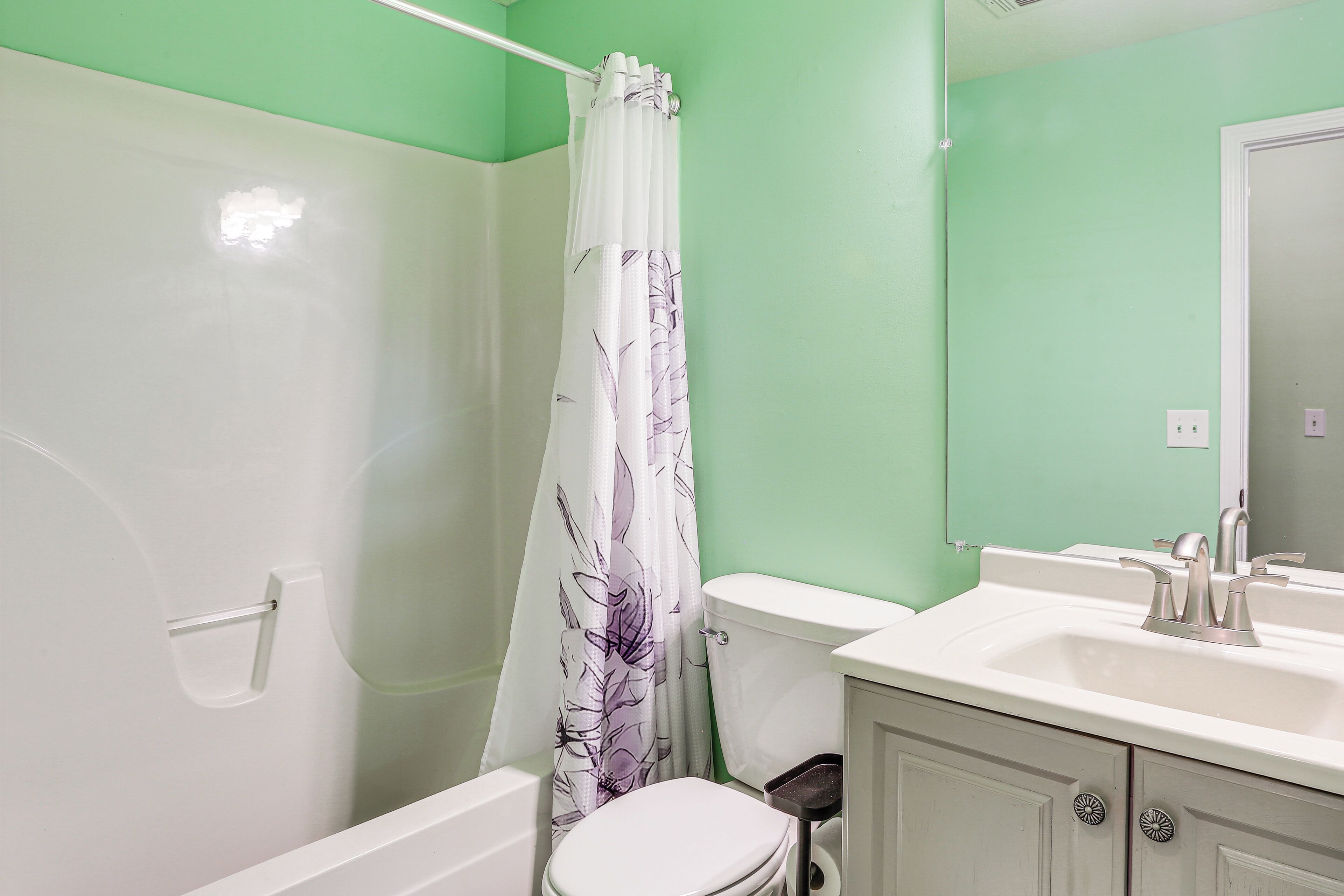 A bathroom with a white bathtub, a toilet, and a sink with a mirror above it.