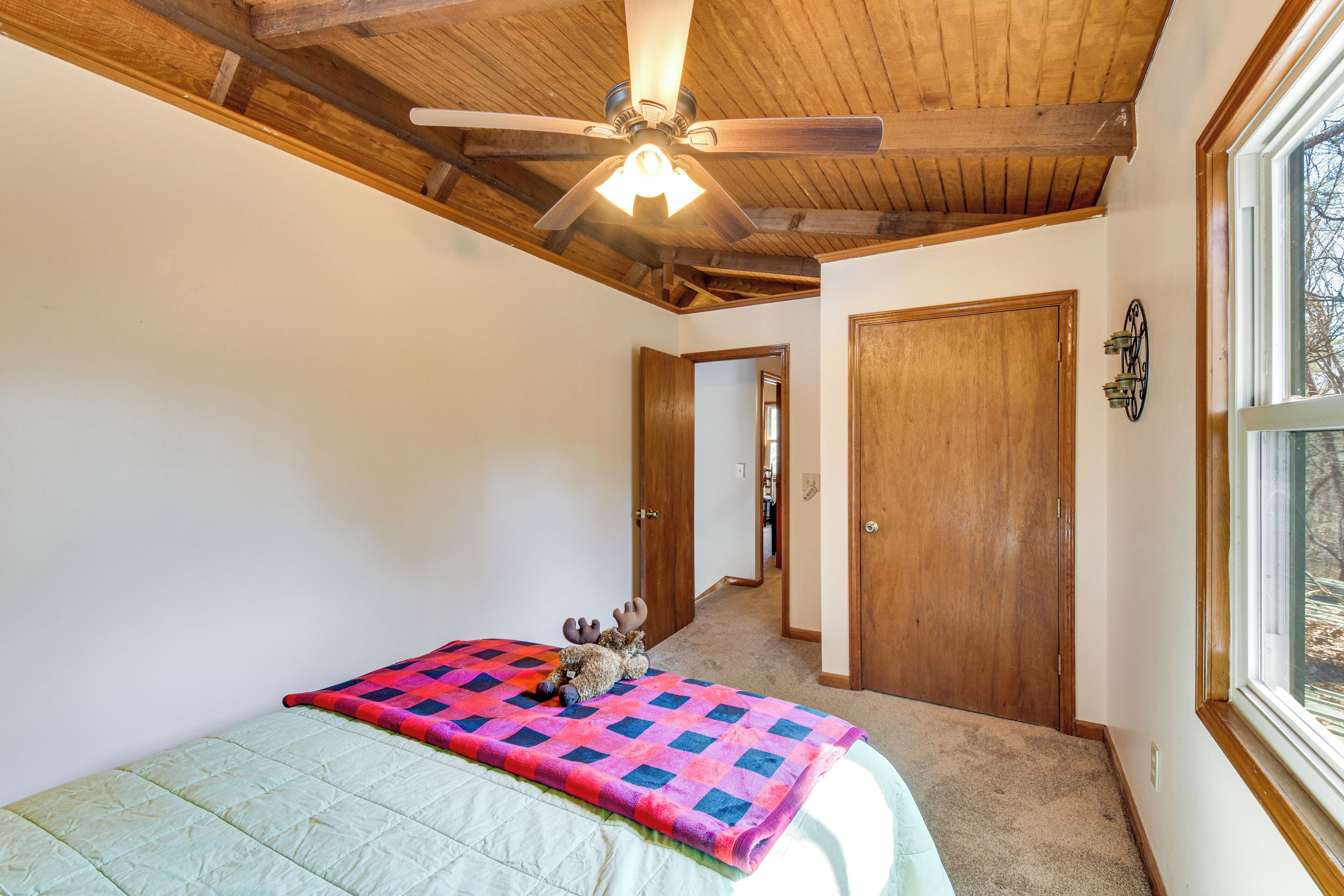 Un dormitorio con cama, ventilador de techo, ventana y puerta.
