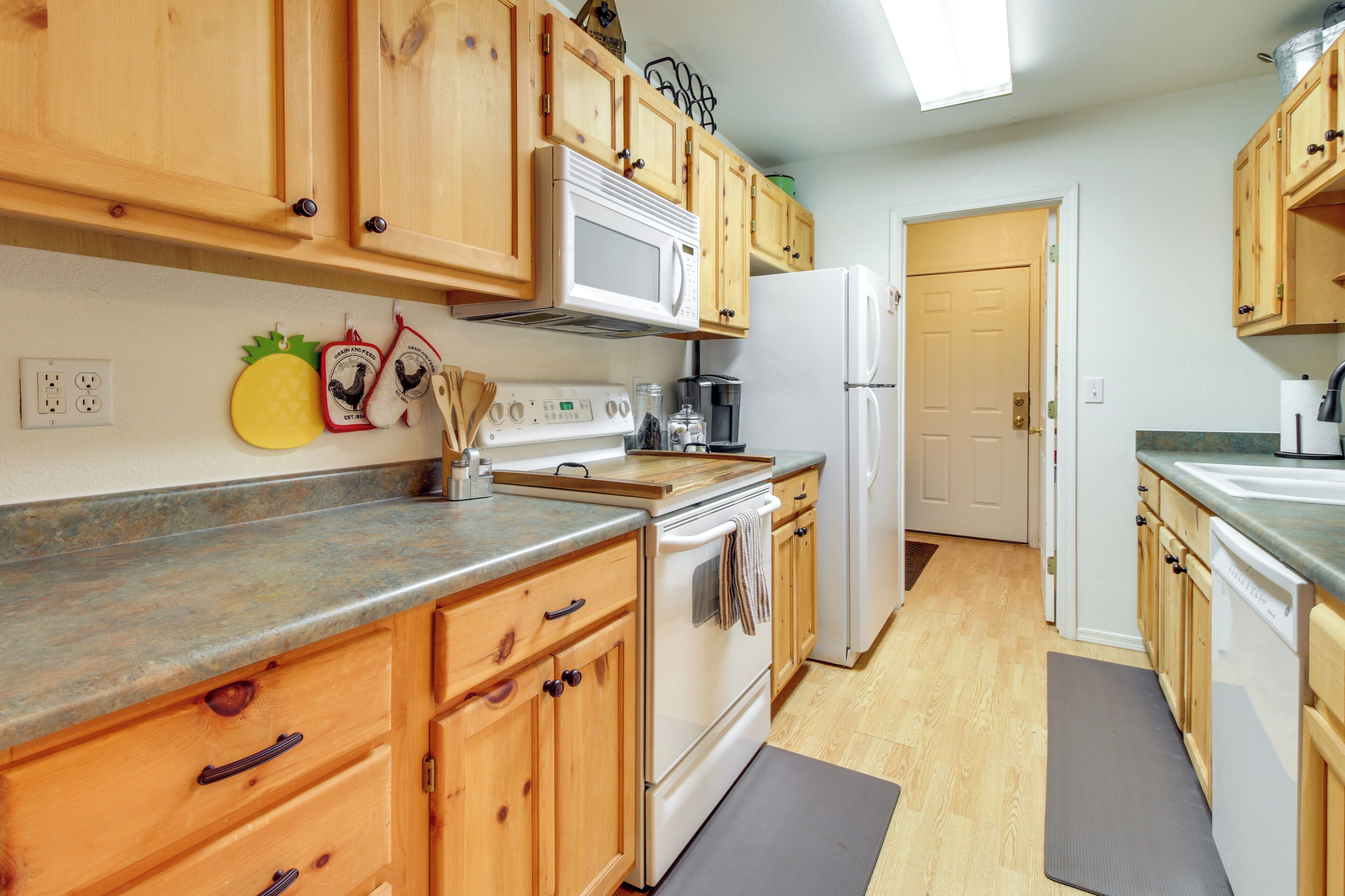 A kitchen with wooden cabinets, a microwave, a stove, a refrigerator, and a coffee maker.