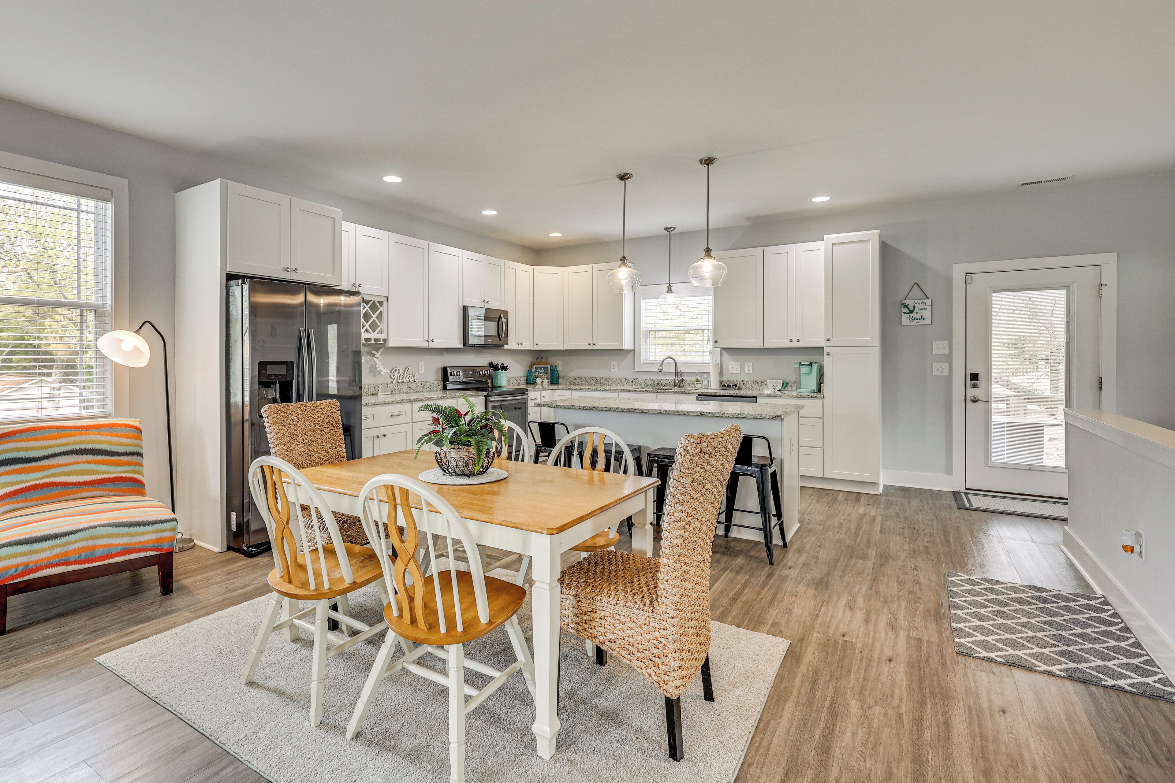 A modern kitchen with white cabinets, a stainless steel refrigerator, and pendant lighting.