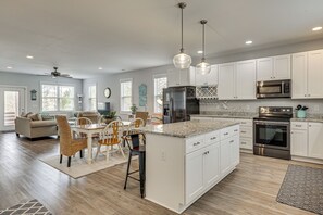 A spacious kitchen with white cabinets, stainless steel appliances, and pendant lighting. - Deck & Games! Pet-friendly Oak Island Home (Oak Island)