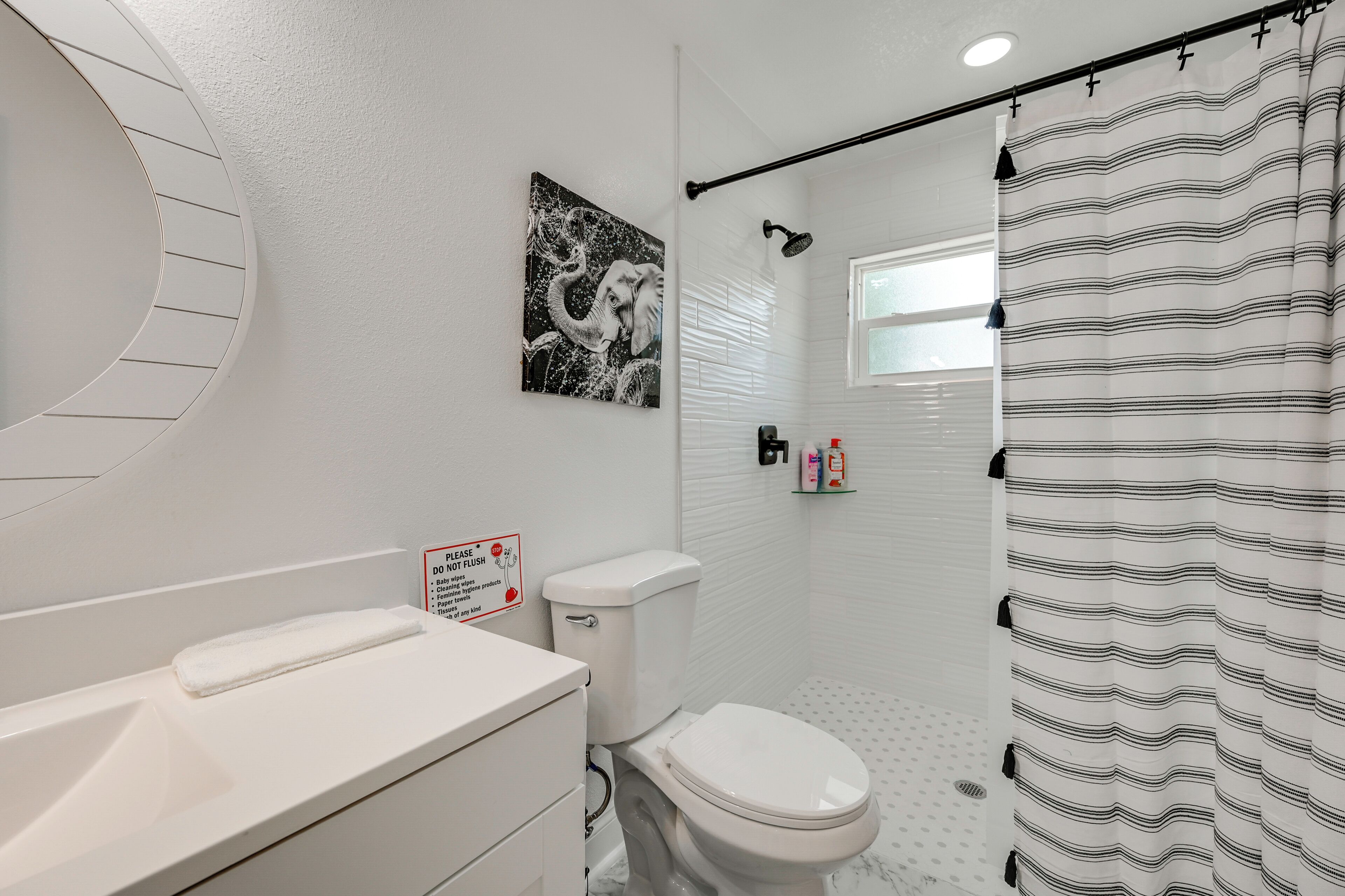 Ein Badezimmer mit Toilette, Waschbecken, Dusche und einem an der Wand hängenden Bild.